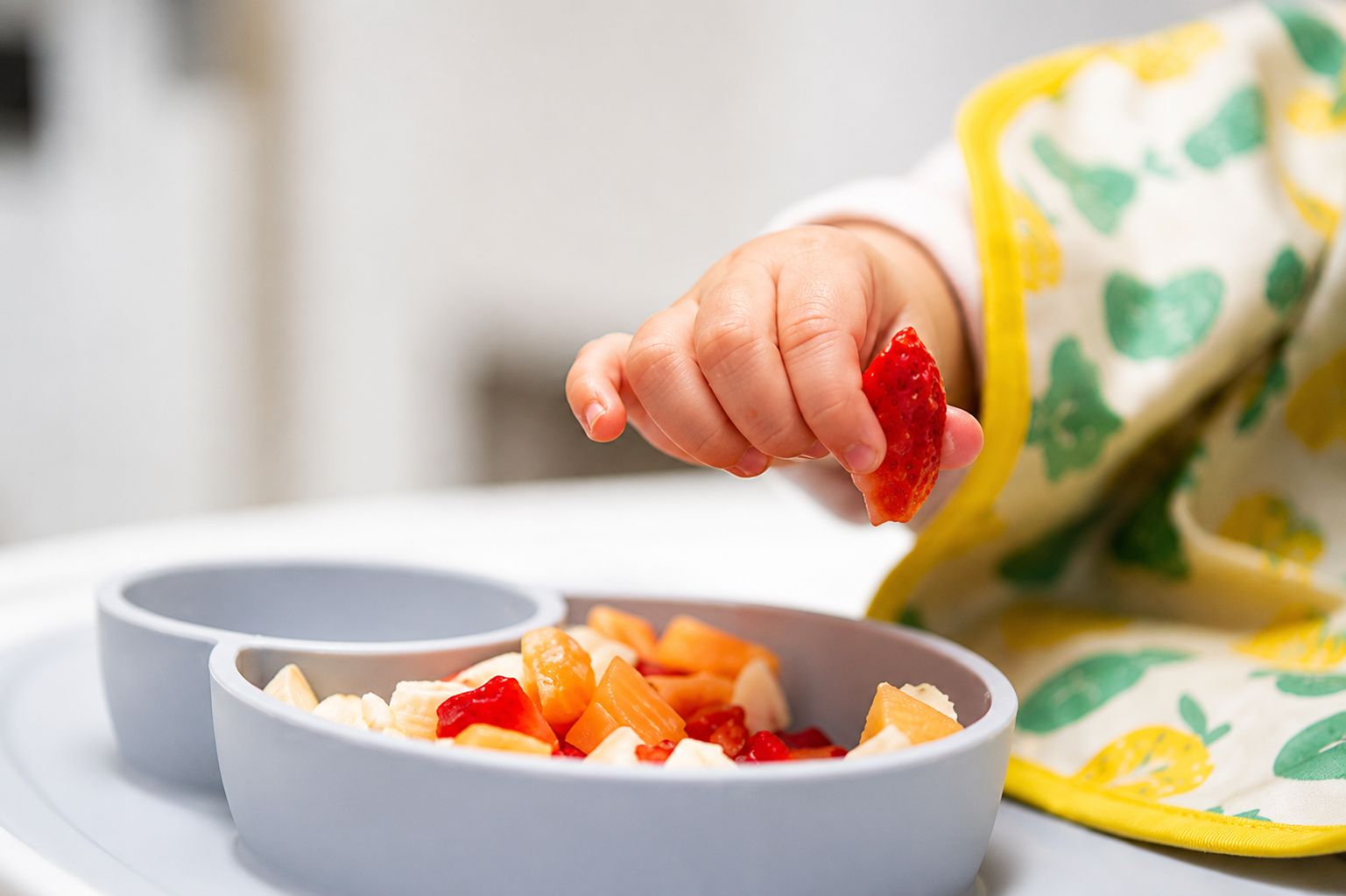 Mother and child cracking an egg into a bowl while baking together